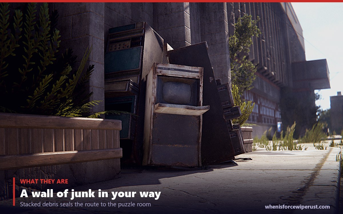 A Rust monument blocker made of stacked appliances and scrap sealing off a route at a red keycard monument in daylight